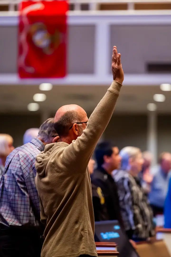 A congregation member raising a hand in prayer during worship