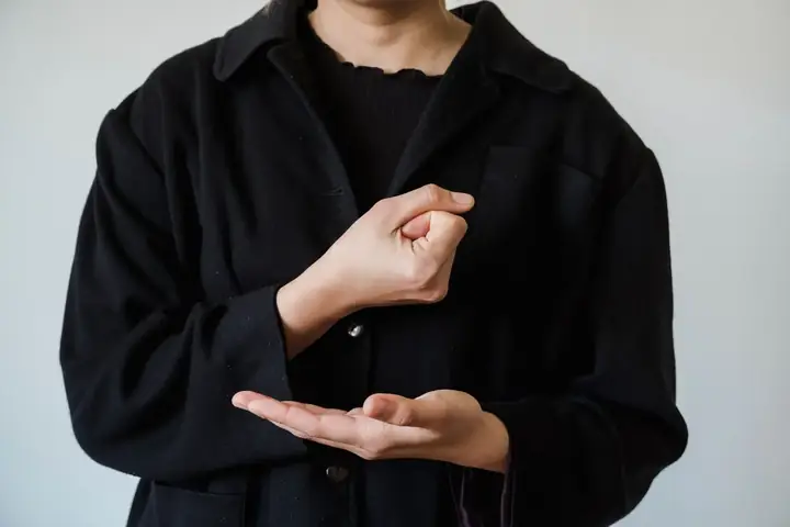 A person practising sign language hand shapes